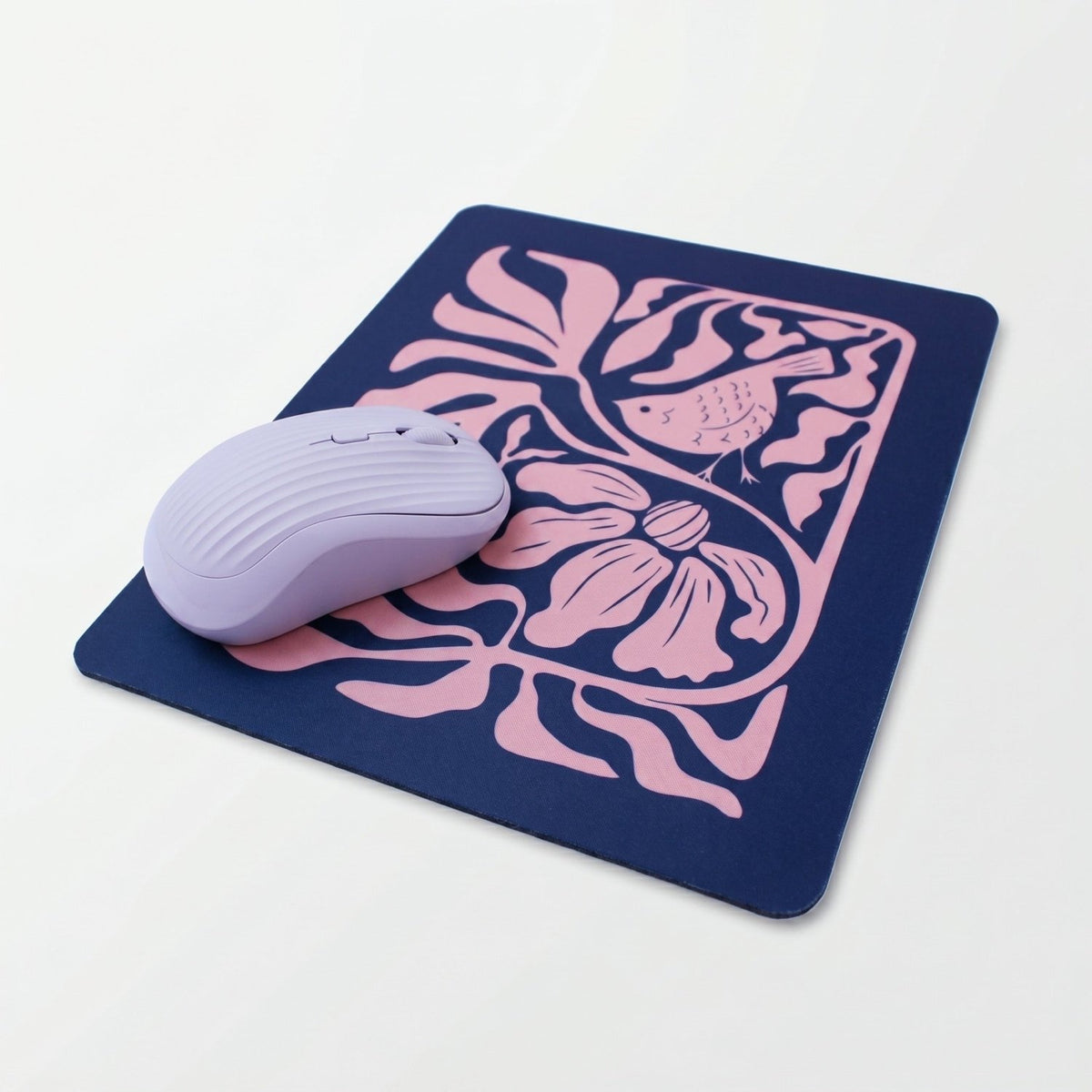Mousepad Trino y Flora de neopreno con ilustración de aves y flores sobre un escritorio